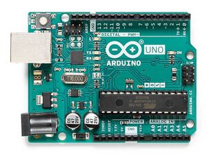 Arduino Uno R3, a green development board about the size of a credit card, with an ATmega328P chip, USB connector, and other features. The photo is taken from the top down.